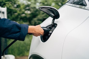 Una mano collega l’auto elettrica al connettore di ricarica EV, il processo di ricarica inizia.