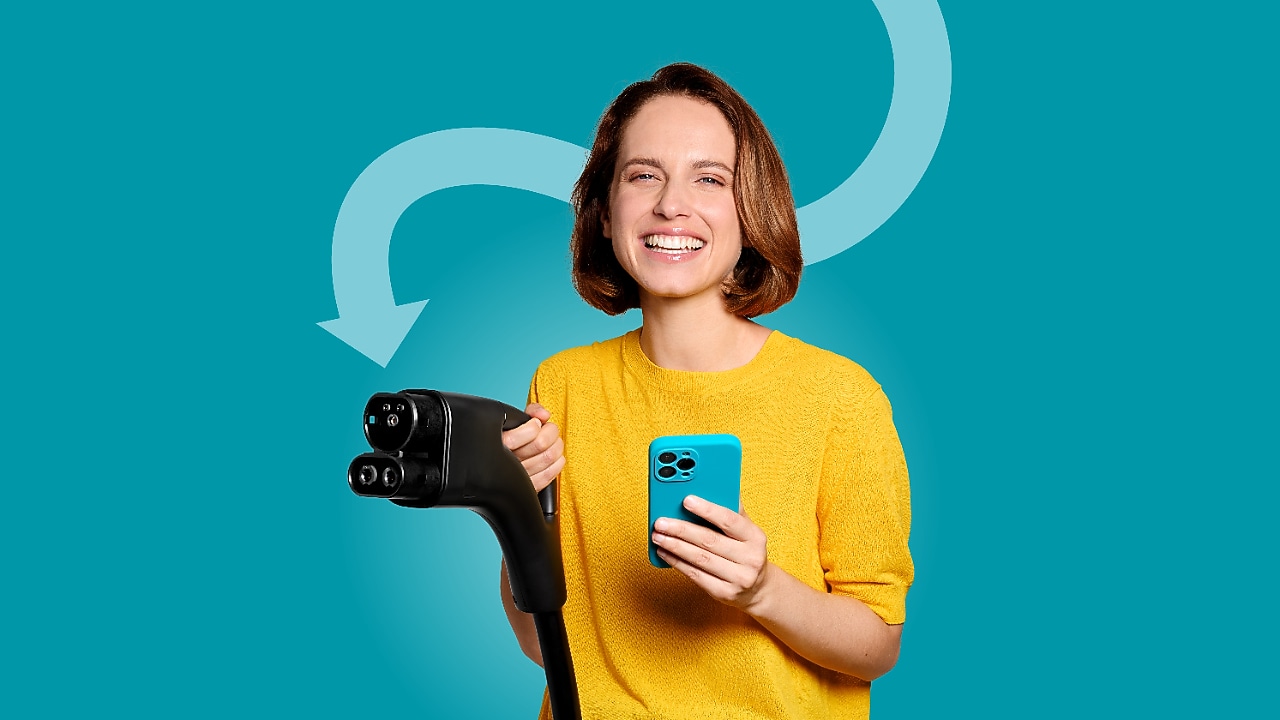 Lächelnde Frau hält ein Smartphone uns EV Ladekabel vor türkisem Hintergrund.